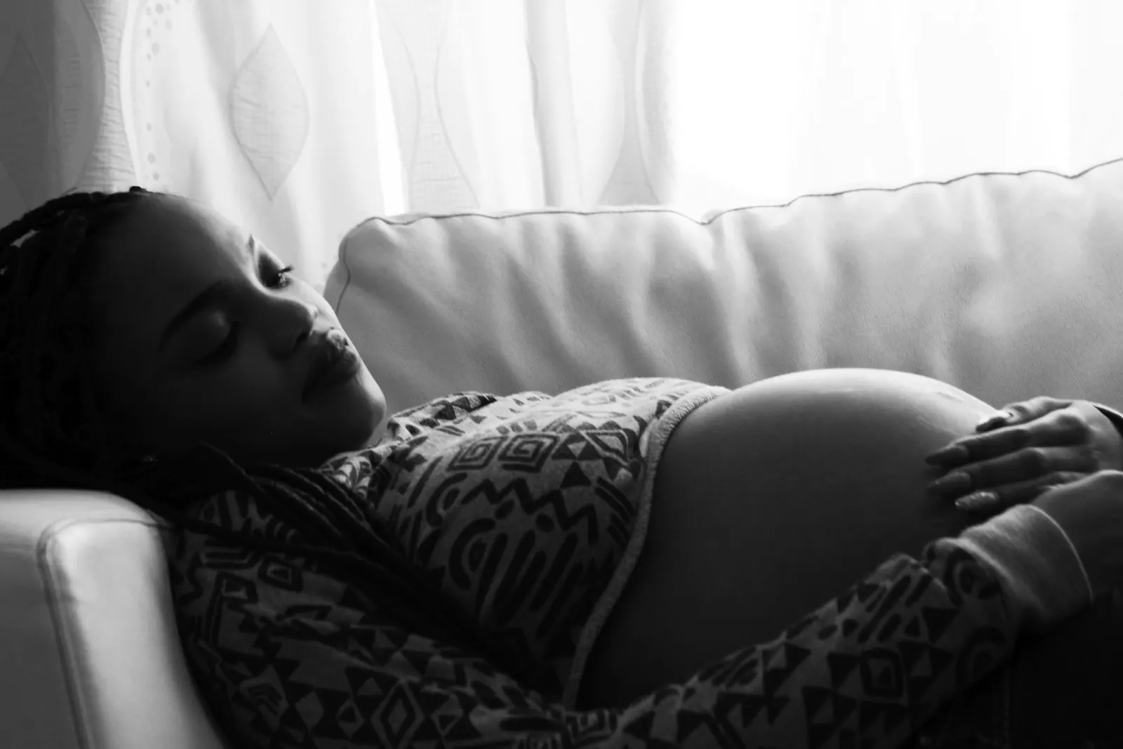 A pregnant woman resting on a sofa with her hands on her belly